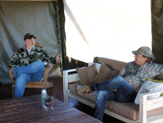 Experience the bond between outdoor enthusiasts as two men engage in lively discussions inside a tent, surrounded by the stunning landscapes of Red Stag Patagonia