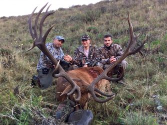 Red Stag Patagonia: Witness the pride and accomplishment as men hold a majestic deer antler, symbolizing their successful hunting expedition in the wilderness